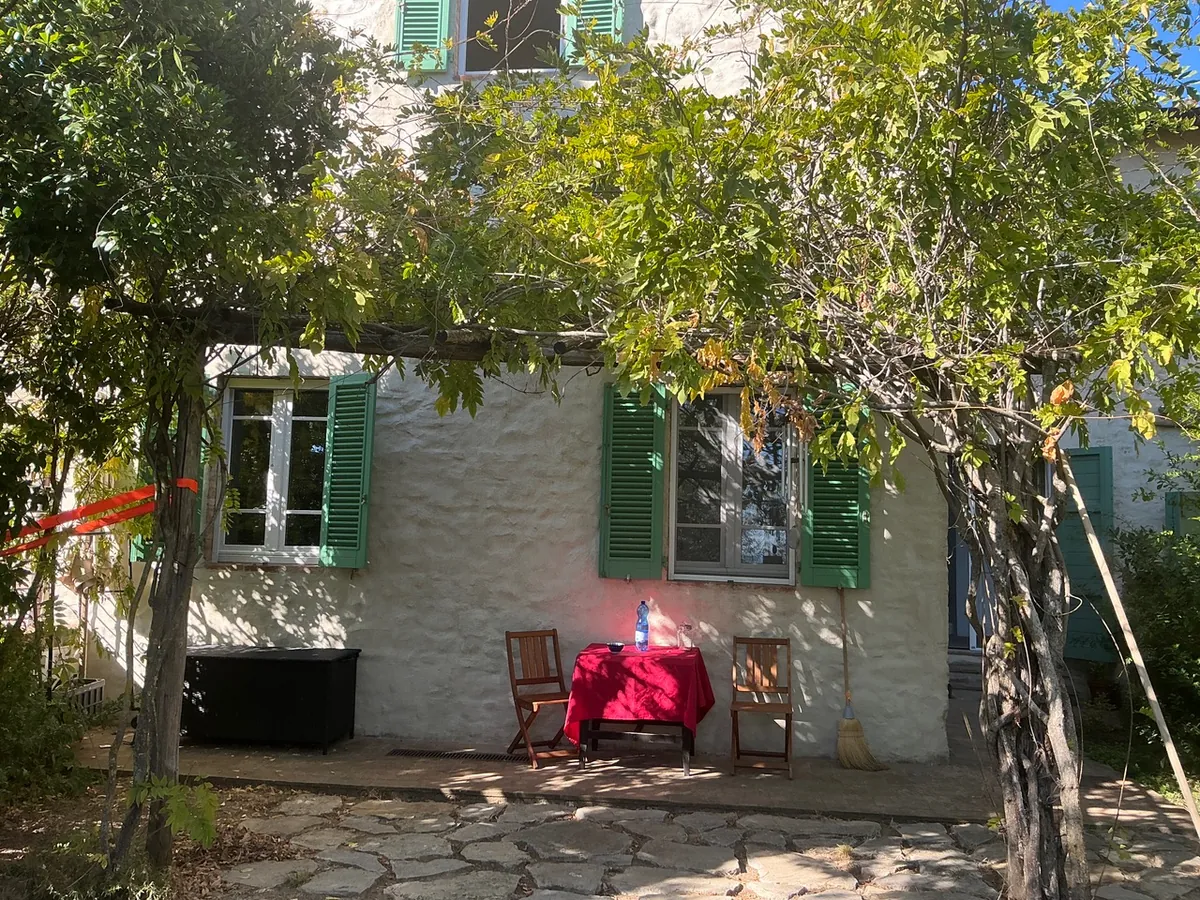 Steinhaus mit grünen Fensterläden unter einer Pergola