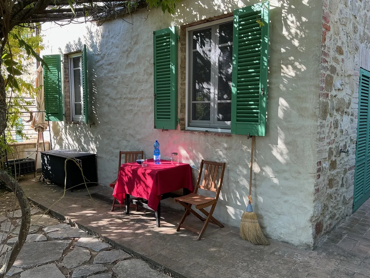 Sitzplatz mit rotem Tisch vor dem Steinhaus